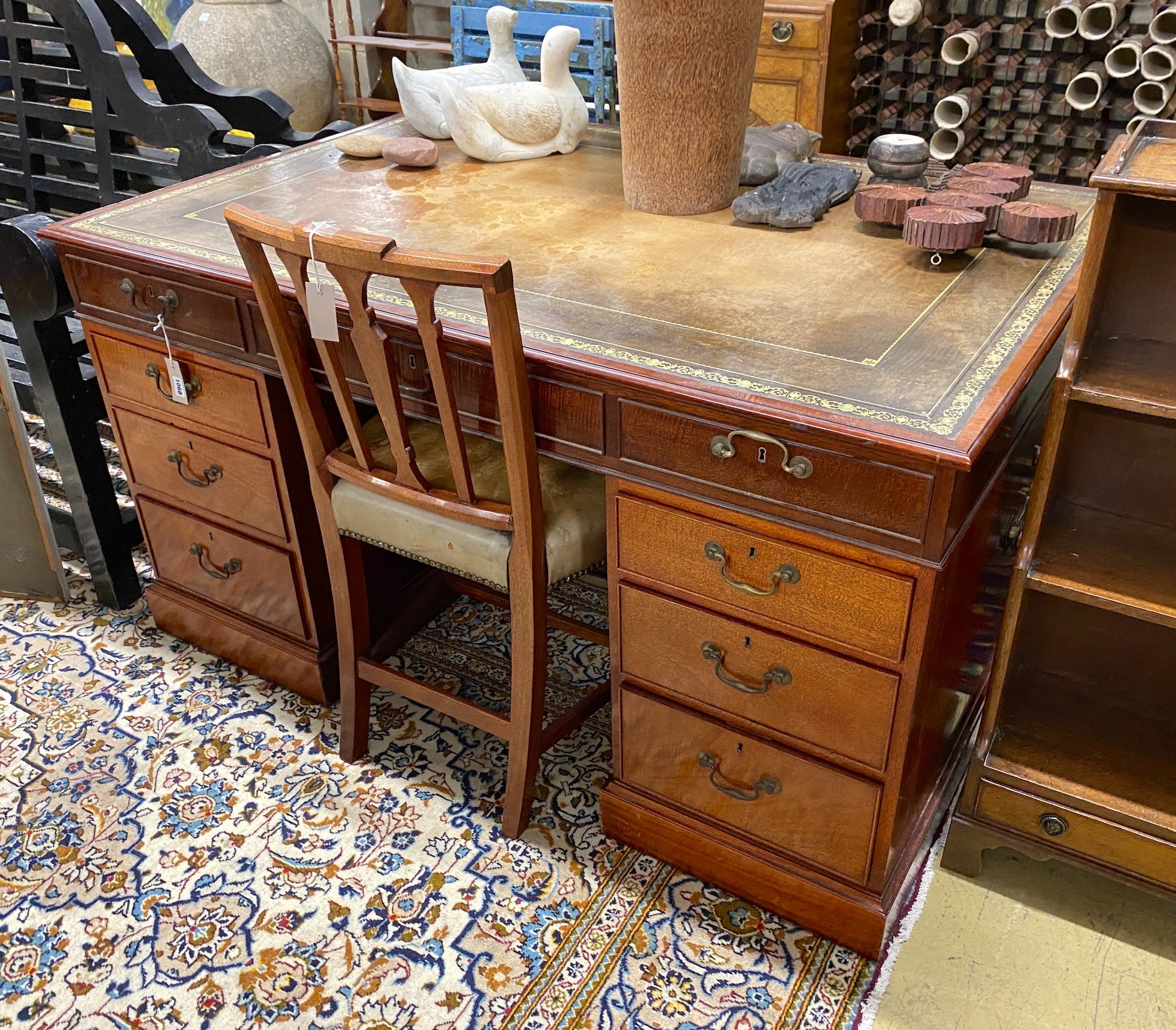 A George III style mahogany pedestal partner's desk by William Tillman, width 142cm, depth 96cm, height 77cm together with a Sheraton style mahogany and tan leather chair, (2)